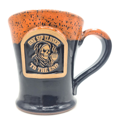 Mug with 'One Sip Closer to the End' design featuring a skull and crossbones on an orange and black speckled background.